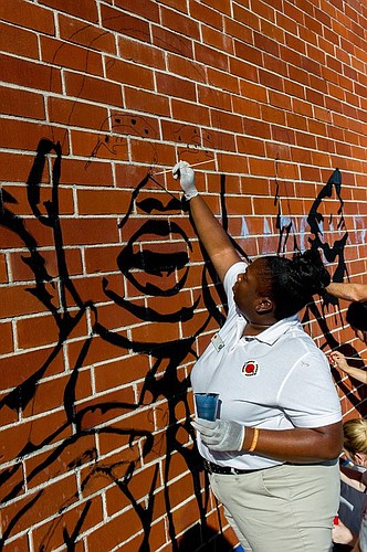 Brittany Fuller of the AmeriCorps City Year program paints in the details of King's face in a mural, which depicts heroes of the student who designed it.