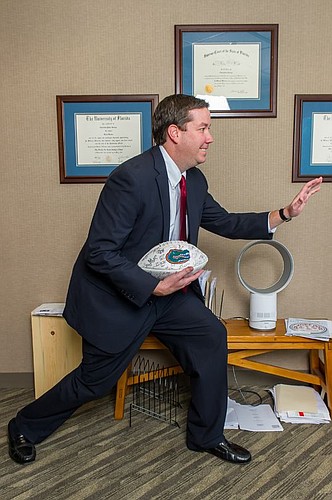 George and his version of the Heisman Trophy pose, as he holds a football autographed by the members of the 2008 Florida Gators National Championship team. George received his undergraduate and law degrees from UF.