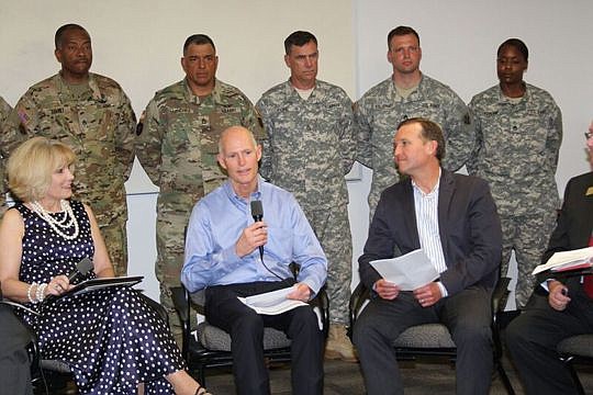 Gov. Rick Scott discusses Enterprise Florida and the Florida Defense Alliance with Kellie Jo Kilberg, chair of the Florida Defense Alliance, left, and Jacksonville Mayor Lenny Curry, right.