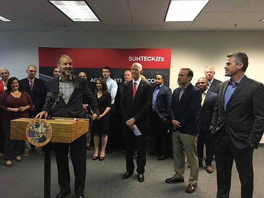 Dave Dallas, chief marketing officer and president of brokerage for SunteckTTS, is watched by Gov. Rick Scott, Mayor Lenny Curry and CEO Ken Forster as he speaks Tuesday. The governor praised the company for adding jobs.