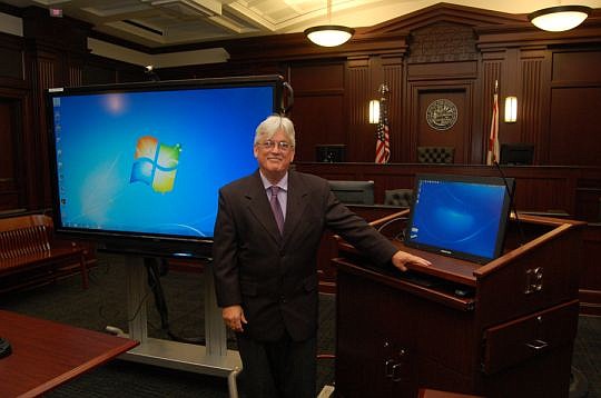 Mike Smith, 4th Judicial Circuit trial court technology officer, with one of the 70-inch high-definition video displays and a video cart that are used to present evidence in court.