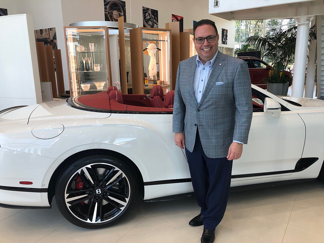 Mario Murgado, owner of Miami-based Murgado Automotive Group Inc, at his dealership in Jacksonville.  With Murgado is the Bentley Continental GT Convertible. (Photo by Karen Brune Mathis)
