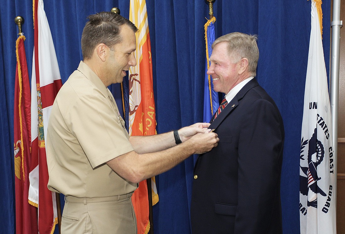 U.S. Navy Capt. Brian Weiss, commanding officer of Naval Air Station Jacksonville, presents the Meritorious Public Service Award to Harrison Conyers, operations manager in the city Military Affairs and Veterans Department.