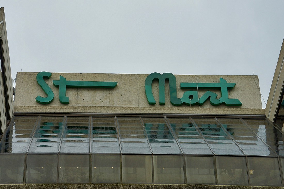 Workers remove the Stein Mart sign from its headquarters on the Downtown Southbank.