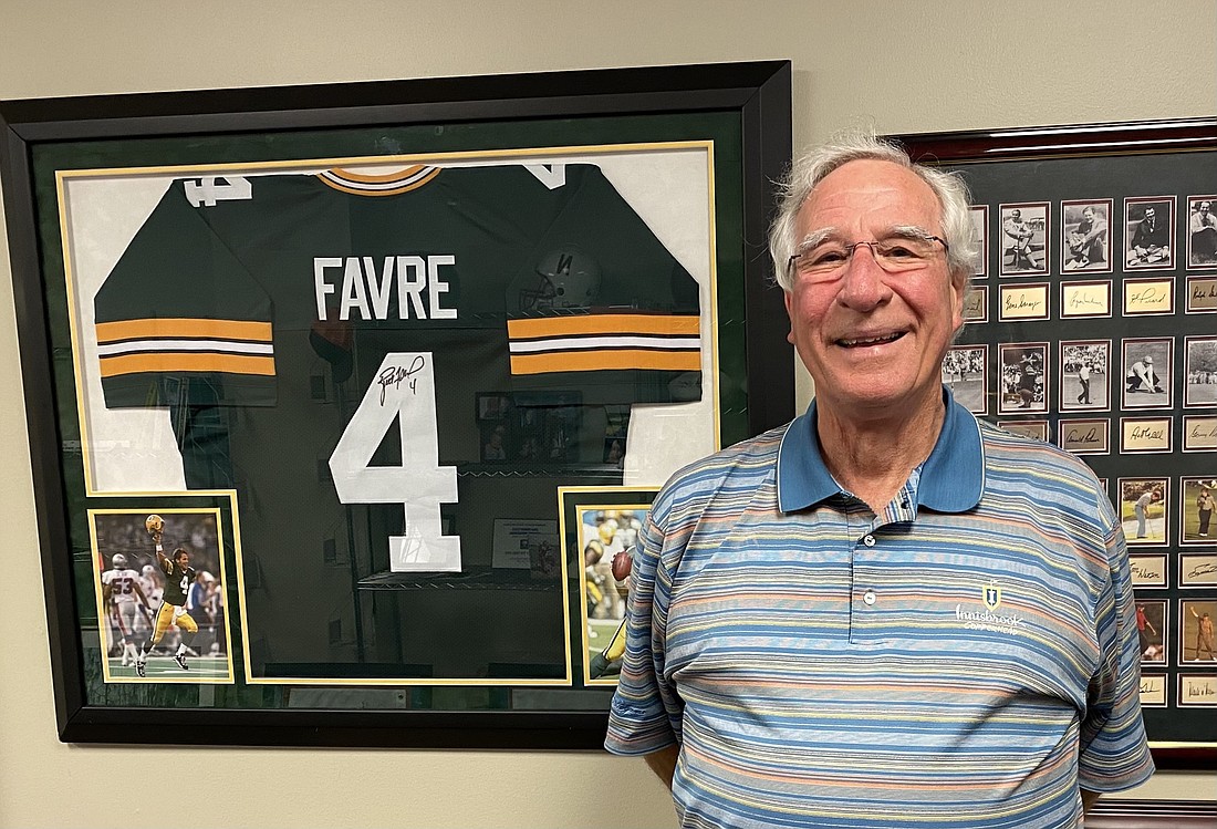 Chuck Parliment stands in front of a wall of his sports memorabilia, including a jersey signed by Green Bay Packers quarterback Brett Favre. Parliment said he is an avid collector and his office was filled with autographed jerseys