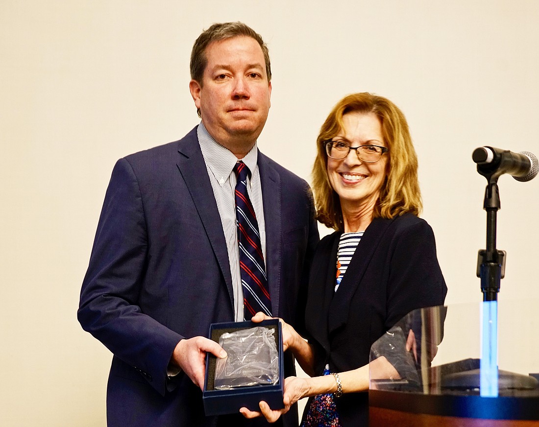 2021 Jacksonville Daily Record Lawyer of the Year Christian George accepts the award from Editor Karen Brune Mathis.