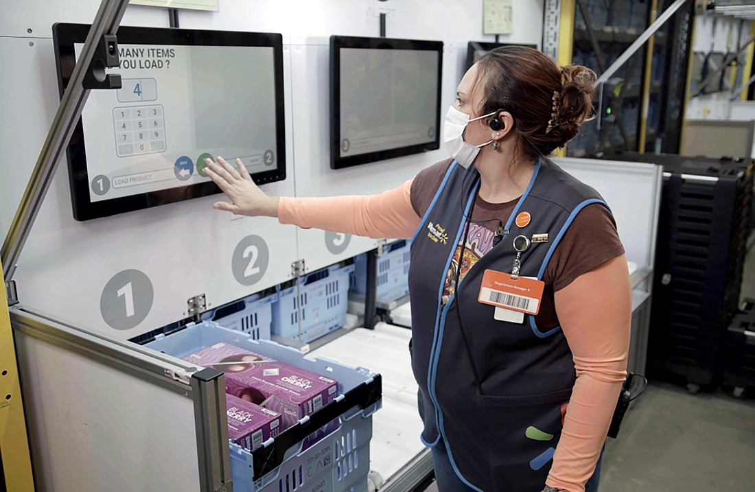Walmart workers at the fulfillment center work with robots to retrieve items.