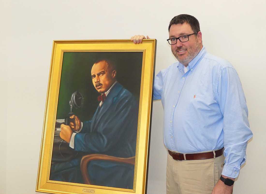 Jacksonville Bar Association Executive Director Craig Shoup with a portrait of James Weldon Johnson, part of the â€œPath to Unityâ€ exhibit at the Duval County Courthouse.