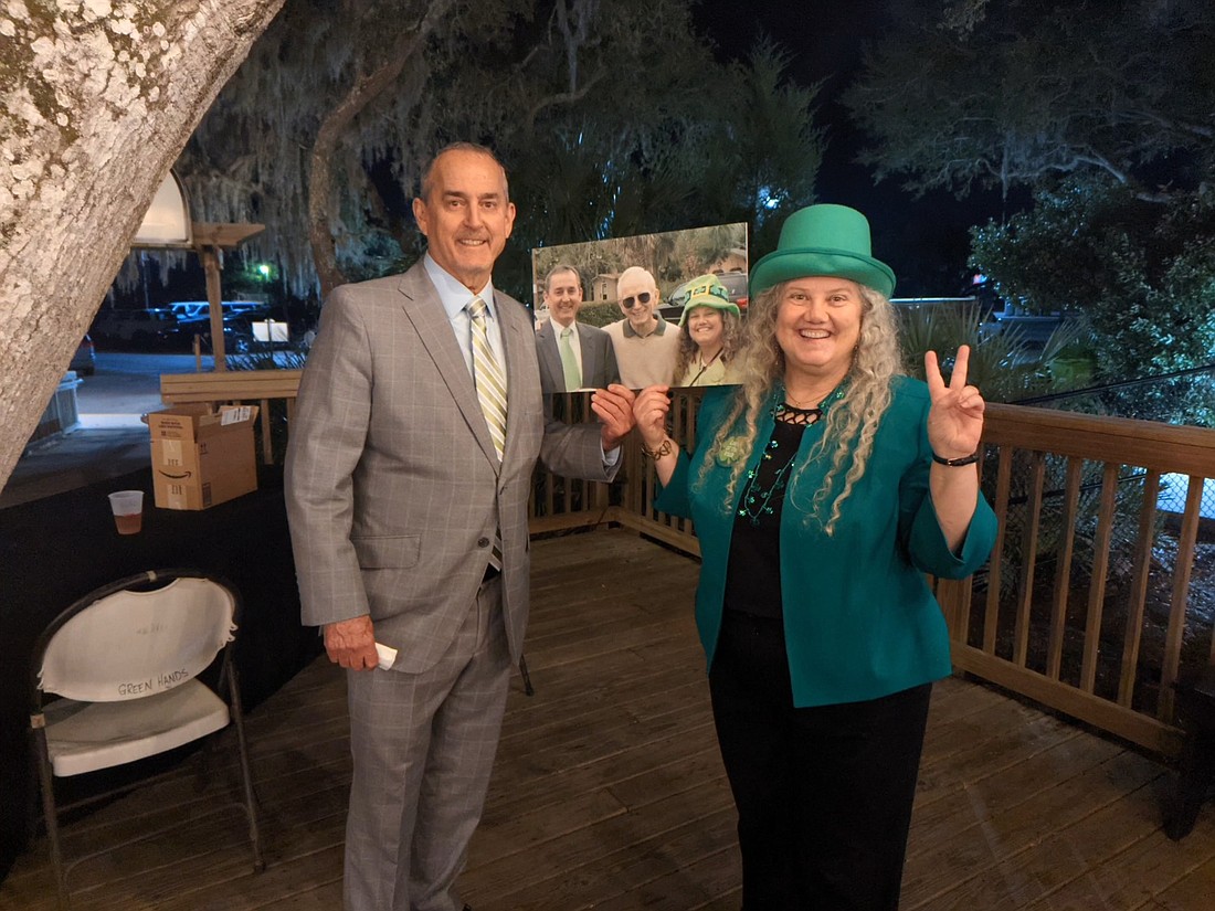 Patrick Canan of Canan Law and Megan Wall, managing attorney at St. Johns County Legal Aid, at theÂ St. Patrickâ€™s Day benefit. They are holding a photo of themselves and the late Senior Circuit Judge Richard Watson.
