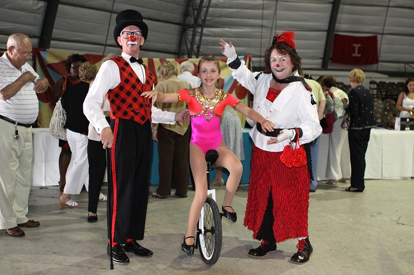 Robin Eurich and Karen Bell pose with Morgan Campbell as she rides a unicycle.