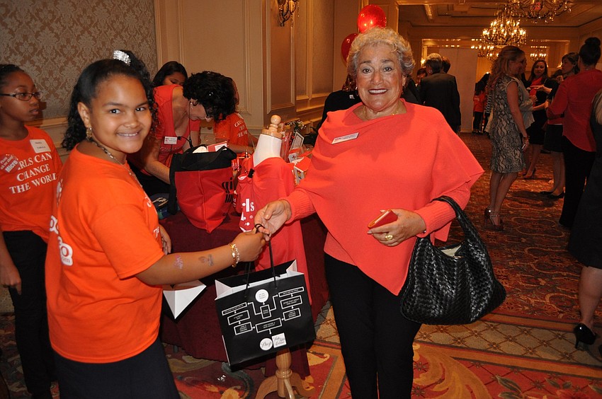 Rheann hands Susan Dweck her bag of goods she bought while at the 25th Celebration Luncheon.