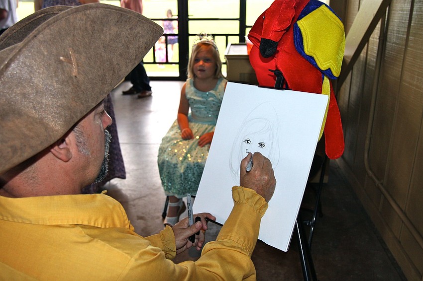 Laine Yahraus, 6, has her portrait drawn by Michael James White.