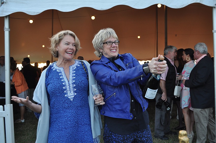 Caroline Farrington stands back as Marjorie Floyd tries to pop open a bottle of champagne.