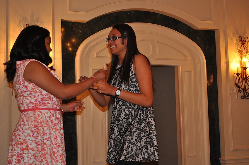 Shayla Brown passes down her Girls Inc. bracelet to Zandy Sanders.