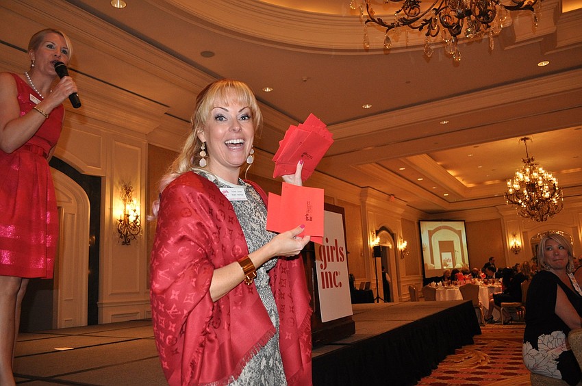 Susan Jones holds up a bunch of red envelopes with donations for Girls Inc. inside.