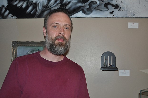 Kirk Doerfler poses near his work, a collection of miniature models