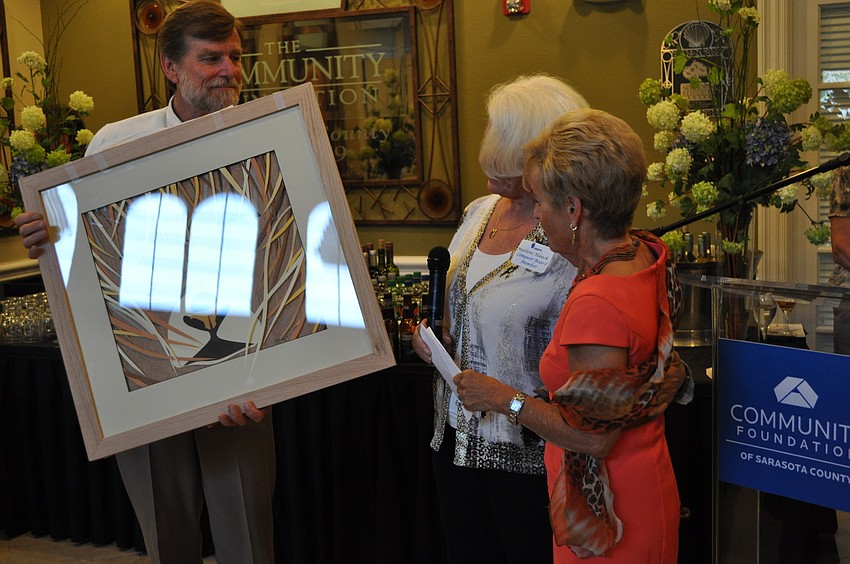 Jack Donoghue and Marlene Hauck present a David Peterson work of art to Bunny Skirboll.