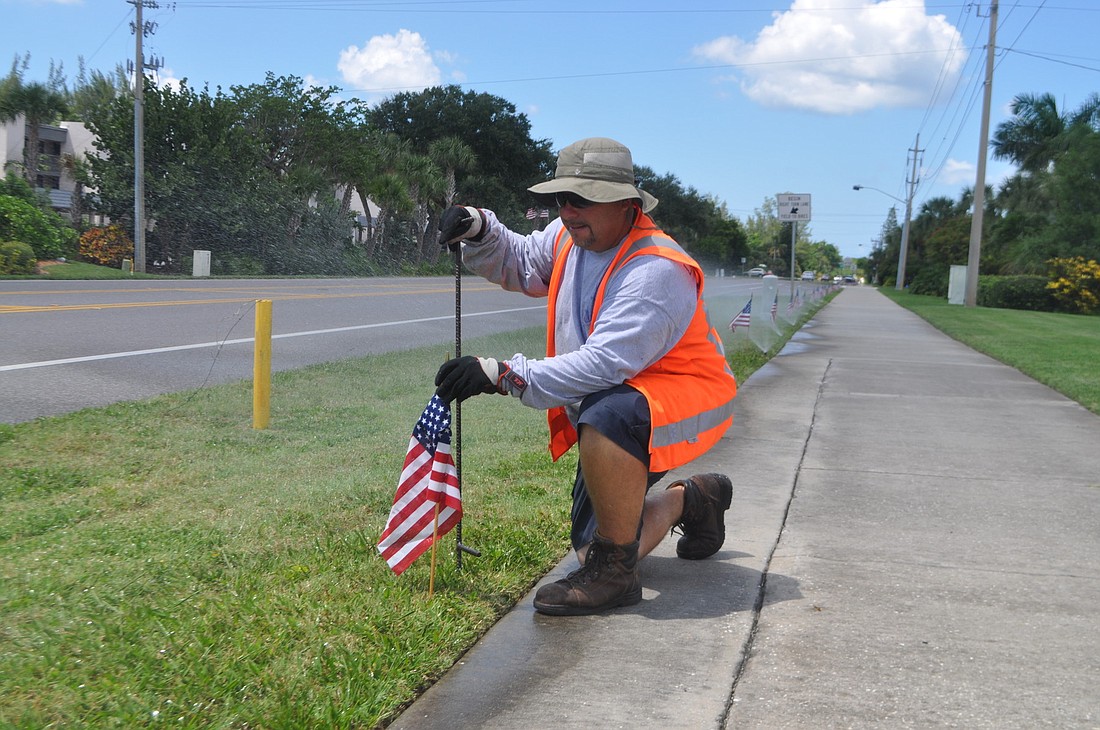 Longboat Key Public Works service worker Tony Porter places flags along Gulf of Mexico Drive Tuesday afternoon in preparation for the 12th anniversary of Sept. 11. Porter received frequent honks of appreciation from motorists.