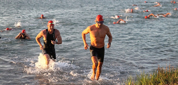 Ed Cornwell, No. 50, and Stephen Berkes, No. 16, make their way out of the bay and onto shore after completing the swimming portion of the sprint triathlon.