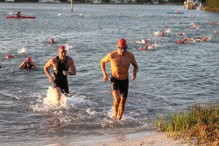 Ed Cornwell, No. 50, and Stephen Berkes, No. 16, make their way out of the bay and onto shore after completing the swimming portion of the sprint triathlon.