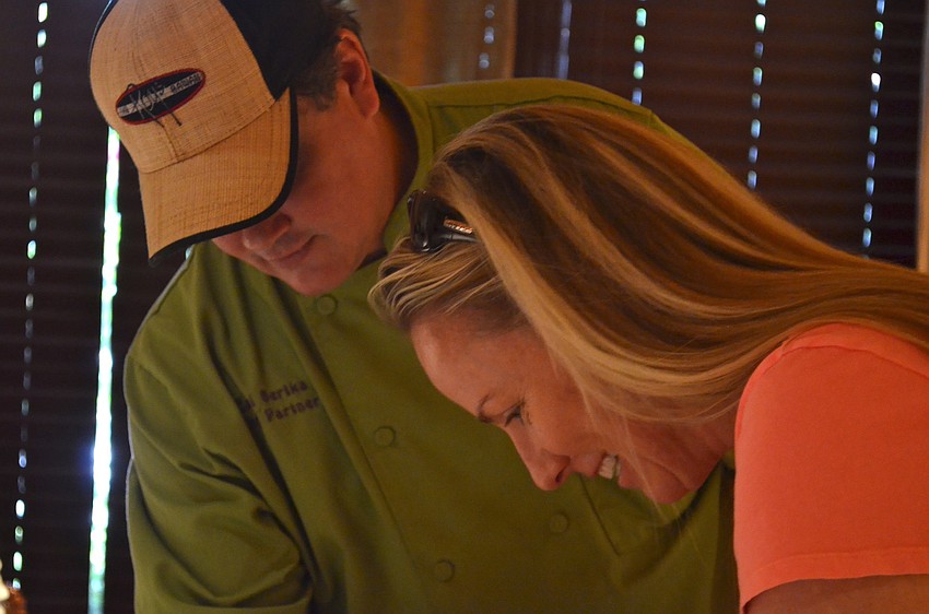 Chef Carl Bertka helps Tricia Bolds create a roll of sushi.