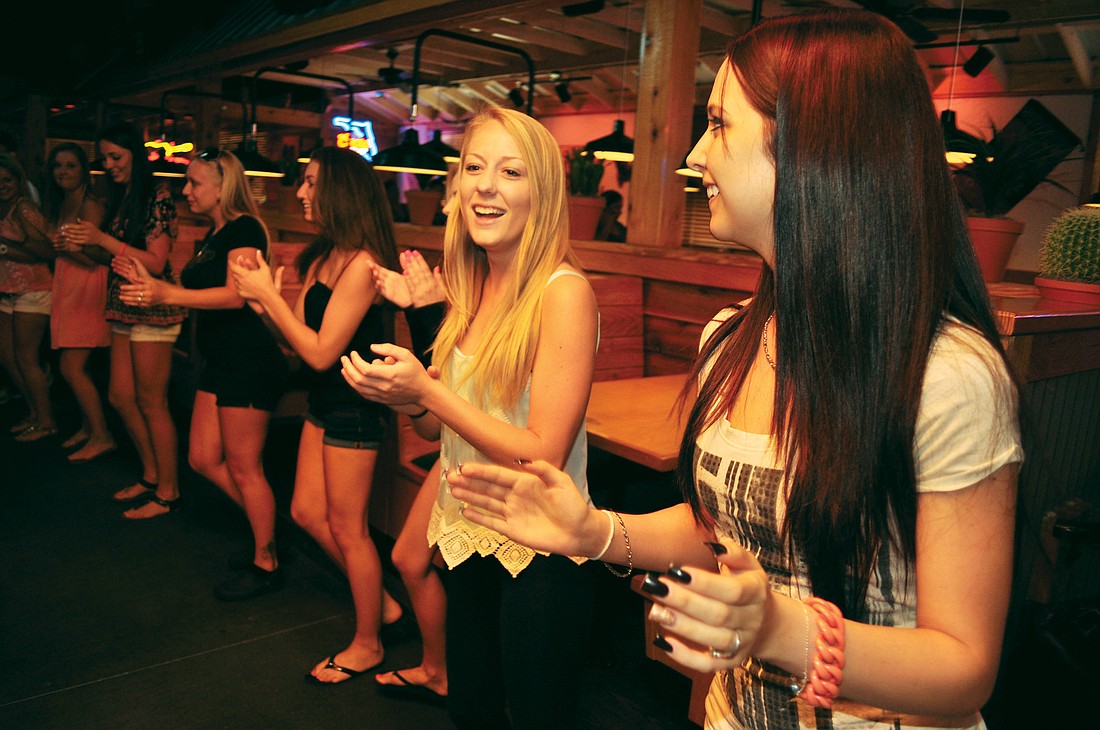 Braden River High School graduates Tessa Ummel, center, and Brittney Lesperance, right, practice a line dance during a staff meeting at the Texas Roadhouse.