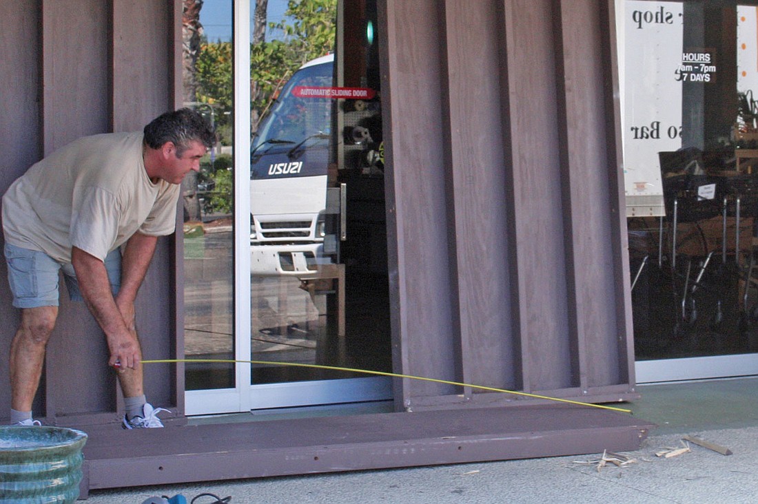 Dezso Ferenczy worked on placing hurricane shutters over the doors to The Market, which closed Tuesday, May 27, 2008. File photo.