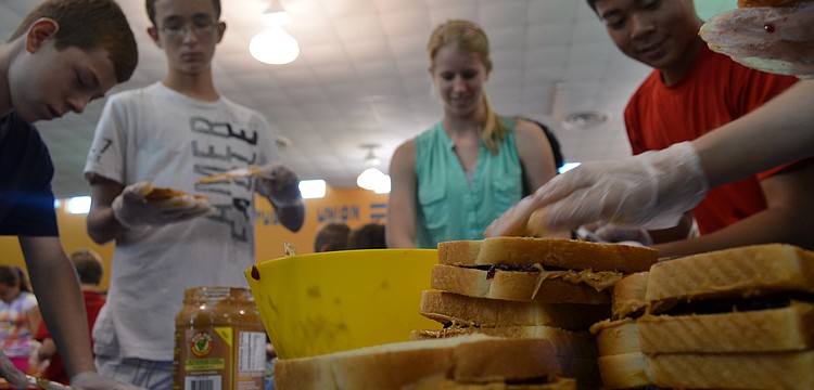 Eight graders Bart Hillerich, Eric Mc Kinnon, senior and table captain Jenny Mooney and eight grader Phillip Tran make sandwiches to break the Guinness World Record.
