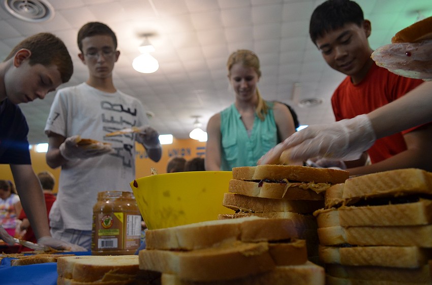 Eight graders Bart Hillerich, Eric Mc Kinnon, senior and table captain Jenny Mooney and eight grader Phillip Tran make sandwiches to break the Guinness World Record.