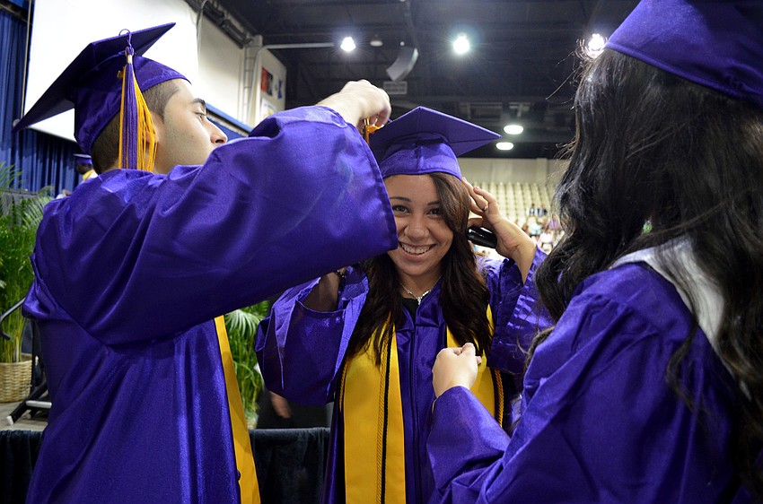 Sergen Altas and Amy Galloza help Camila Alvarado with her cap.