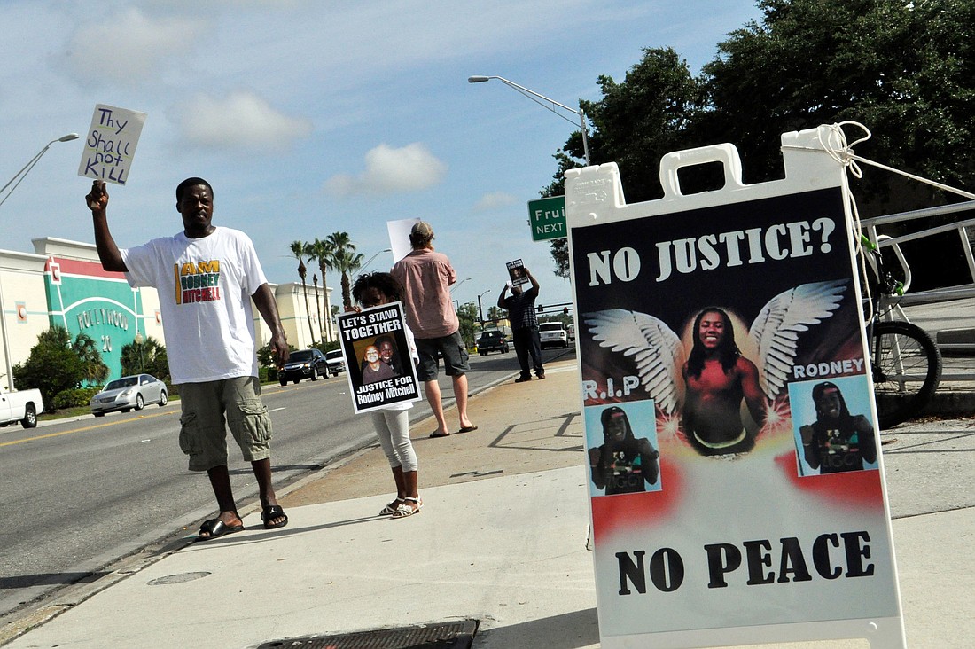 Ernest Arnold and Jayla Rivers hold signs during a protest at the corner of Washngton Boulevard and Main Street.