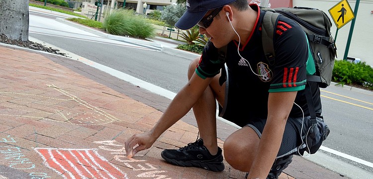 Ramiro Chavez draws on the sidewalk in Five Points Park.