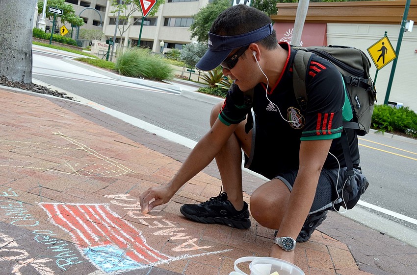 Ramiro Chavez draws on the sidewalk in Five Points Park.