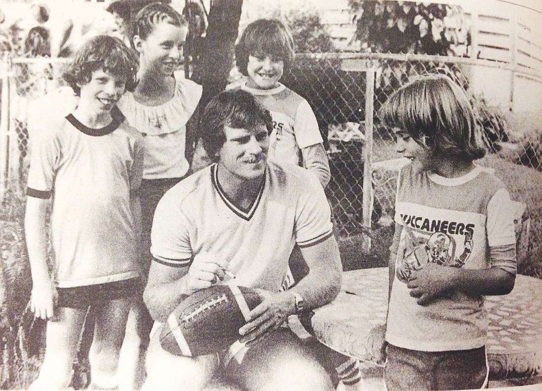 Mark Cotney, of the Tampa Bay Bucs, autographs a football for The Out-of-Door Academy students Bill Lineweaver, Kay Lineweaver, Robbie Malkin and Jonnie Malkin.