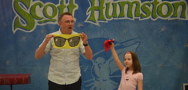 Veronica Van Cleave, 6, helps magician Scott Humston with a magic trick.