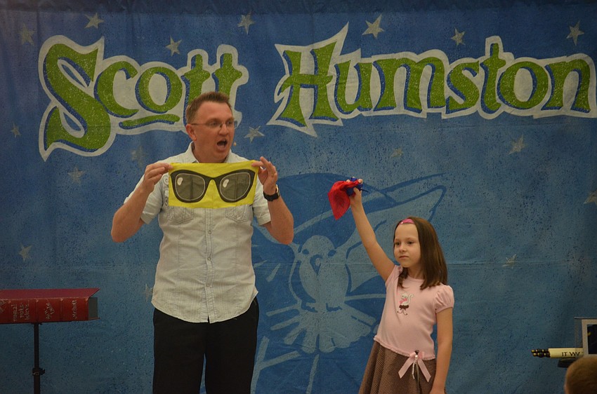 Veronica Van Cleave, 6, helps magician Scott Humston with a magic trick.