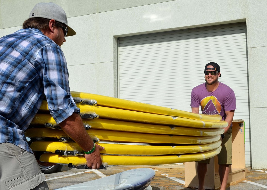 Ryan Bodie and John Bowman unload a stack of new custom surfboards before the expansion of their nonprofit surf camp to Sarasota.