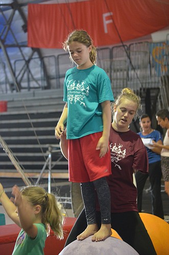 Camp counselor Alison Krizen helps camper Sarah Windom, 10, balance on the globes.