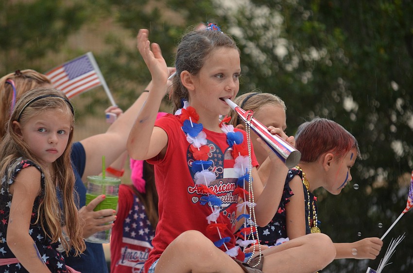 Children wave to the crowd while riding in the parade.