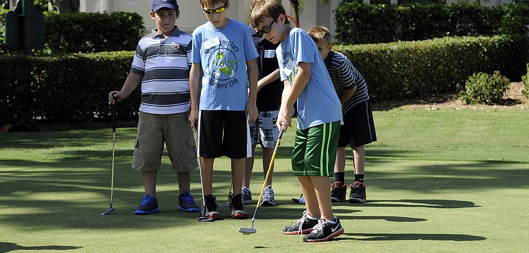 Nine-year-old Logen Beane attempts a putt while the rest of his flight looks on.
