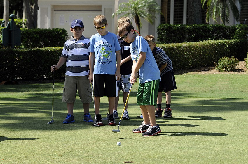 Nine-year-old Logen Beane attempts a putt while the rest of his flight looks on.