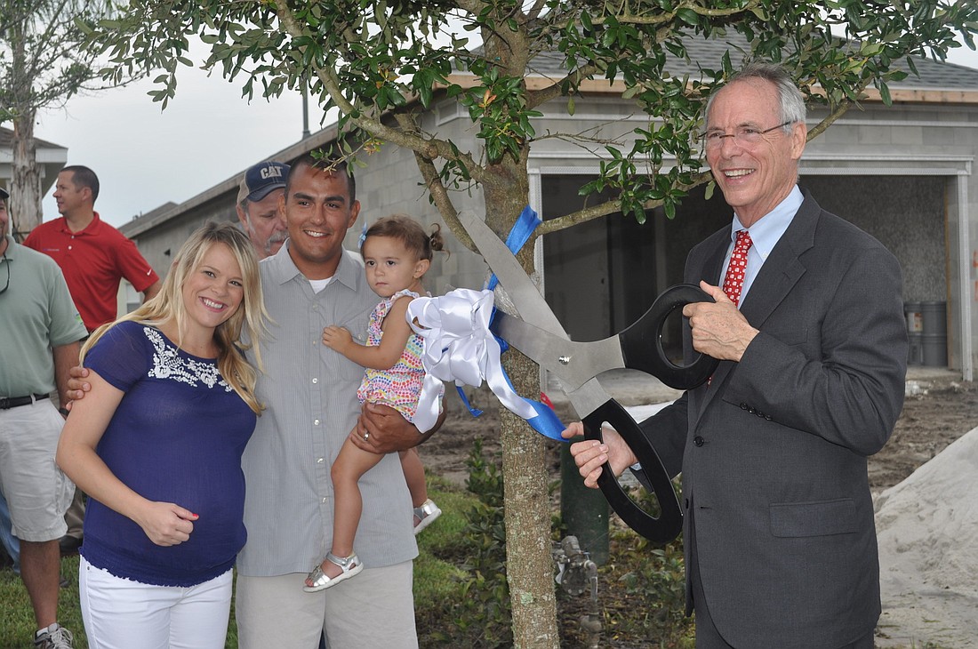 Stephanie, Dane and Eva Martinez watch as Neal Communities President and CEO Pat Neal cuts the tape on a tree signifying the companyÃ¢â‚¬â„¢s 9,000th home. The tree is located in the MartinezesÃ¢â‚¬â„¢ backyard.