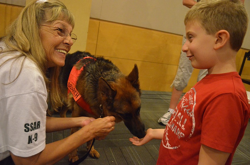 Pat Abrams shows Ayden Shapoiro, 7, how to feed Search & Rescue K-9 Ana.