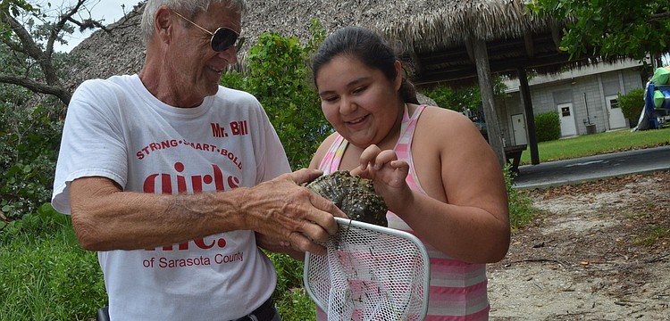 Bill Johnson holds out a 40- year-old snail for Chrissy Lopez to touch. Chrissy found the snail in the bay.