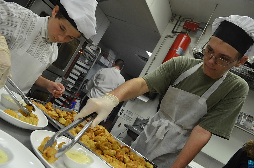 Nicolas Duverneuil, 13, and Max Aston, 15, put artichokes on plates and hand them to the servers to take out to the guests.