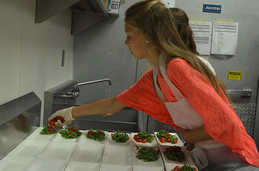 Samantha Reisky, 11, tops the arugula salad with tomatoes.