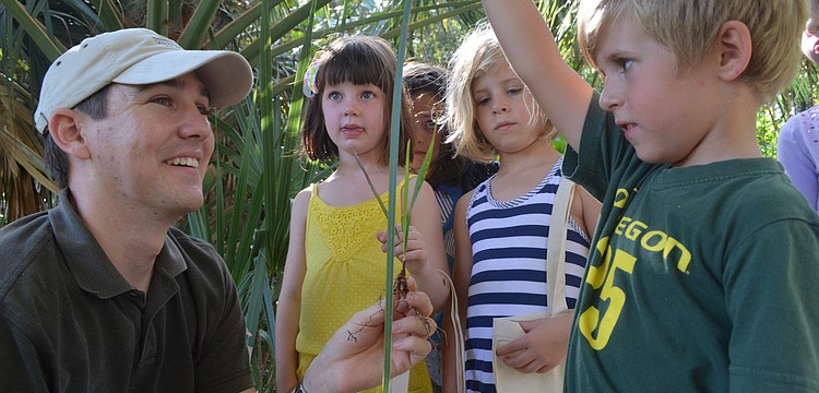 Land Stewart of the Conservation Foundation of the Gulf Coast Lee Amos teaches Claire Toale, 5, Chelsea McKay 5, and her brother Liam, 4, and other children about the plants and trees that grow around them.