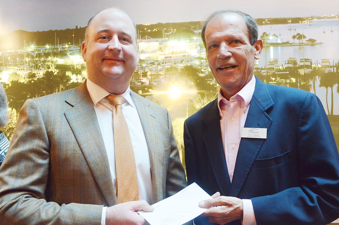Michael Saunders & Co. President Drayton Saunders gives Doug Kerr, of the Venice Symphony, a grant check.