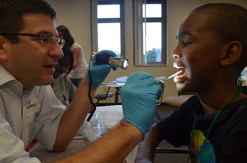 David Freeman of Freeman Orthodontists checks 11-year-old Milan Smithâ€™s teeth for cavities.  This is the third year Freeman has participated in Day of Hope.