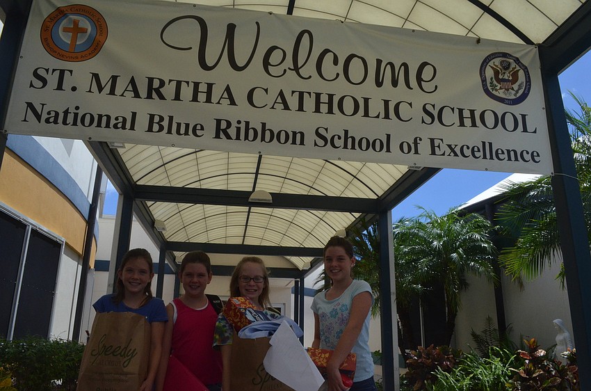 Katherine Lumpkin, 10, her sister Mallory, 8, Avery Blechta, 10, and her sister Grace, 11, bring supplies to St. Martha for the Back to School Bash.